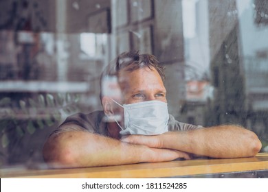 Man Wear White Protective Mask, Looking Outside Through Window, Afraid Stress Hope In Eyes, Recovery From The Illness In Home, Self Isolation Due To Global COVID 19 Coronavirus Pandemic