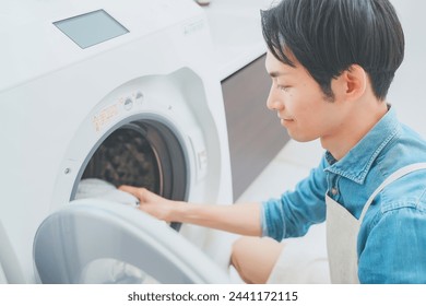 Man wearing apron doing laundry - Powered by Shutterstock