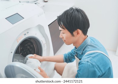 Man wearing apron doing laundry - Powered by Shutterstock