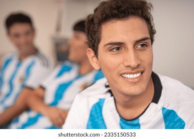 Man wearing the Argentina national soccer team jersey, his friends in the back with the jersey. - Powered by Shutterstock