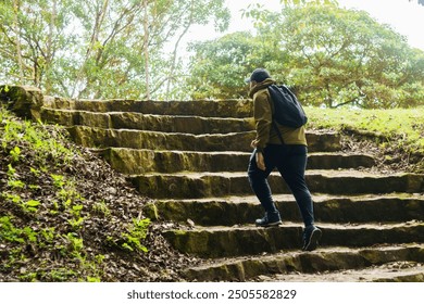A man wearing a backpack is climbing a set of stone steps in a forest