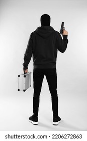 Man Wearing Black Balaclava With Metal Briefcase And Gun On Light Grey Background, Back View