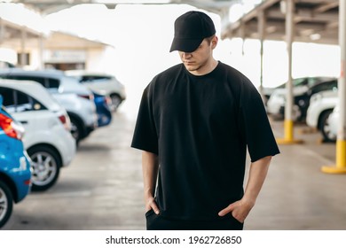 Man wearing black blank t-shirt and a black baseball cap with space for your logo or design. Mock up - Shutterstock ID 1962726850