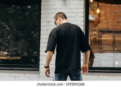 Man wearing black blank t-shirt with space for your logo or design. Mock up - Shutterstock ID 1993092368