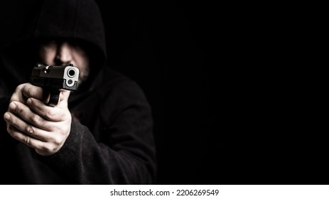 Man Wearing Black Hoodie Holds Gun. Criminal Offense, Armed Robbery, Gun Violence Concept. 