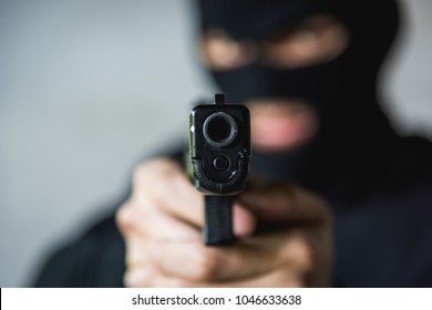 The man wearing black masked he is robbery using hands holding gun pointing aiming for threat ready to shooting killer, Robber concept, focus on the gun
