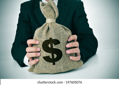a man wearing a black suit holding a burlap money bag