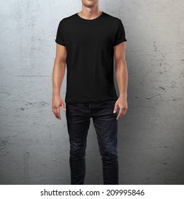 Man wearing black t-shirt. Concrete wall background