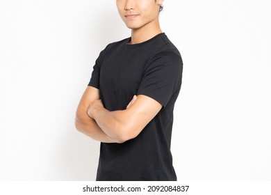Man wearing a black T-shirt standing in front of a white background with his arms folded