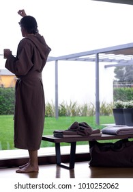 Man Wearing A Brown Bathrobe Having A Coffee Mug Looking Outside The Window