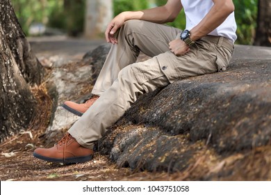 Man wearing brown cargo pants and sitting in the nature park
