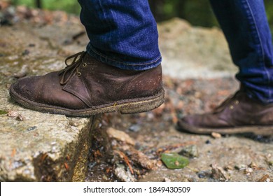 A man wearing brown chukka boots climbing up steps