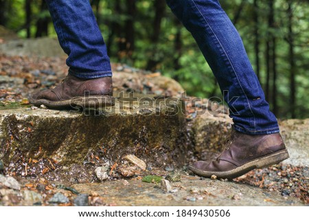 A man wearing brown chukka boots climbing up steps