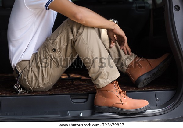 Man wearing cargo pants sitting in suv car parking\
in the nature park