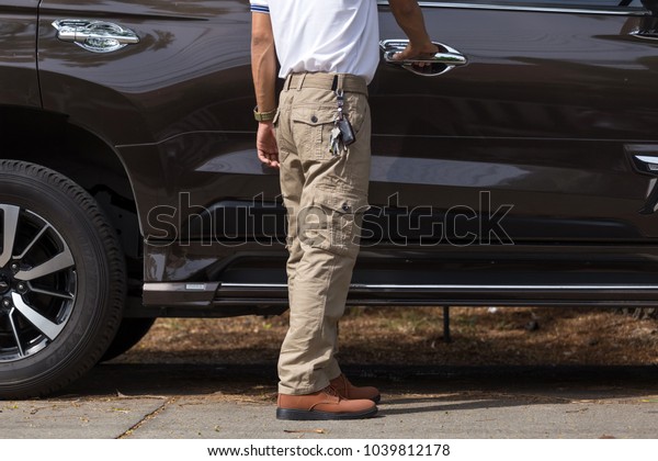 Man wearing cargo pants with suv car parking in the\
nature park