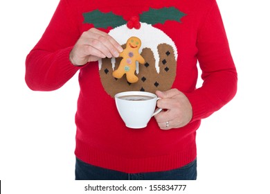 Man Wearing A Christmas Jumper About To Dip A Gingerbread Man In A Cup Of Hot Chocolate, Isolated Against A White Background.