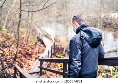 Man Wearing A Corona Virus Mask While Walking Outdoors In The Nature In Winter Or Autumn. Young Person Hiking The Forest During Coronavirus Pandemic And Quarantine. Happy Hiker With Facemask.