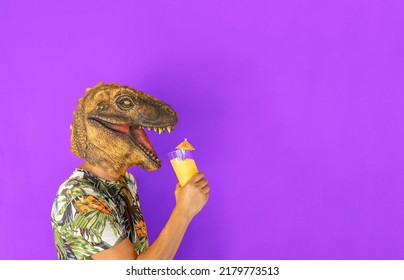 Man Wearing Dinosaur Animal Head Mask Drinking Cocktail Or Fruits Juice Isolated On Green Background.