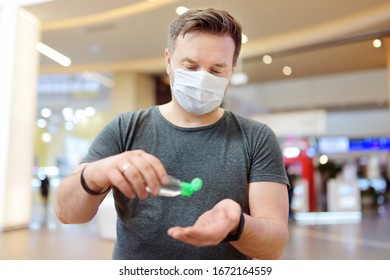 Man Wearing Disposable Medical Face Mask Makes Disinfection Of Hands With Sanitizer In Airport, Supermarket Or Other Public Place. Safety During Coronavirus Outbreak. Epidemic Of Virus Covid.