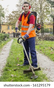 Man Wearing  Ear Protectors Mowing Grass In The Backyard With Petrol Hedge Trimmer