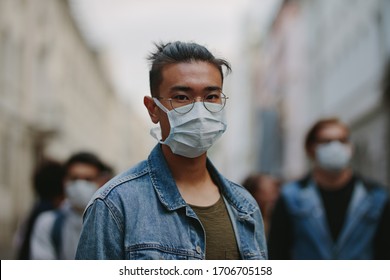 Man wearing a face mask during a global pandemic with coronavirus. Portrait of man with a crowd behind him. - Powered by Shutterstock