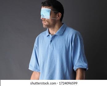 A man wearing a face mask over his eyes. Fake news. Gray background.