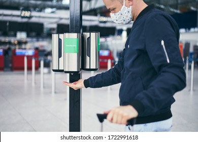 Man wearing face mask and using hand sanitizer at airport. Themes traveling during pandemic, hygiene and personal protection. - Powered by Shutterstock