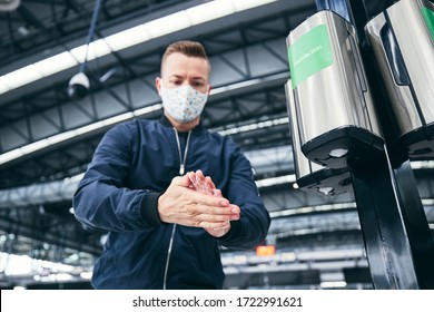 Man wearing face mask and using hand sanitizer at airport. Themes traveling during pandemic, hygiene and personal protection. - Powered by Shutterstock