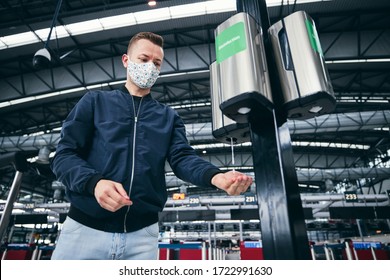 Man wearing face mask and using hand sanitizer at airport. Themes traveling during pandemic, hygiene and personal protection.