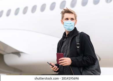 A Man Wearing Face Mask While Standing Next To Airplane With Passport. New Normal Traveling During A Pandemic. Male Passenger Traveling By Plane. Wearing Mask In Aircraft Cabin. Air Travel Covid 19