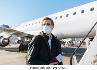 A Man Wearing Face Mask While Standing Next To Airplane With Passport. New Normal Traveling During A Pandemic. Male Passenger Traveling By Plane. Wearing Mask In Aircraft Cabin. Air Travel Covid 19