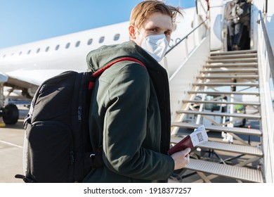 A Man Wearing Face Mask While Standing Next To Airplane With Passport. New Normal Traveling During A Pandemic. Male Passenger Traveling By Plane. Wearing Mask In Aircraft Cabin. Air Travel Covid 19