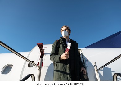 A Man Wearing Face Mask While Standing Next To Airplane With Passport. New Normal Traveling During A Pandemic. Male Passenger Traveling By Plane. Wearing Mask In Aircraft Cabin. Air Travel Covid 19