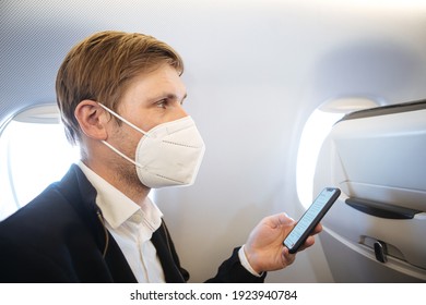 A Man Wearing FFP2 Face Mask While Sitting Into An Airplane. New Normal Traveling During A Pandemic. Male Passenger Traveling By Plane. Wearing N95 Mask In Aircraft Cabin. Air Travel Covid 19