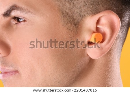 Man wearing foam ear plug, closeup view