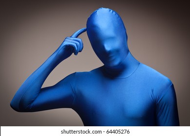 Man Wearing Full Blue Nylon Bodysuit Scratching His Head On A Grey Background.