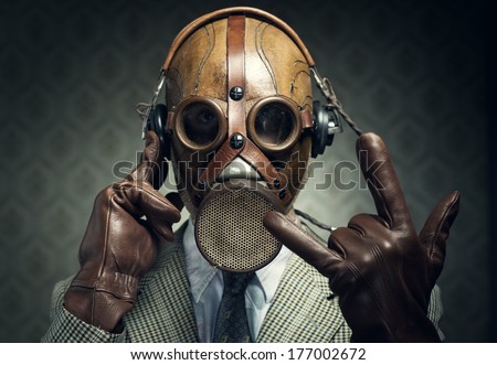 Man wearing gas mask and headphones making rock sign.