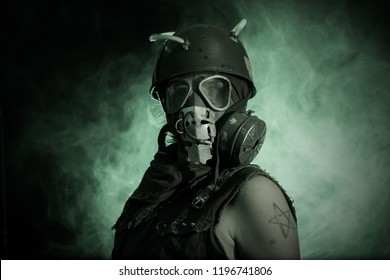 Man wearing gas mask stands in green colored smoke