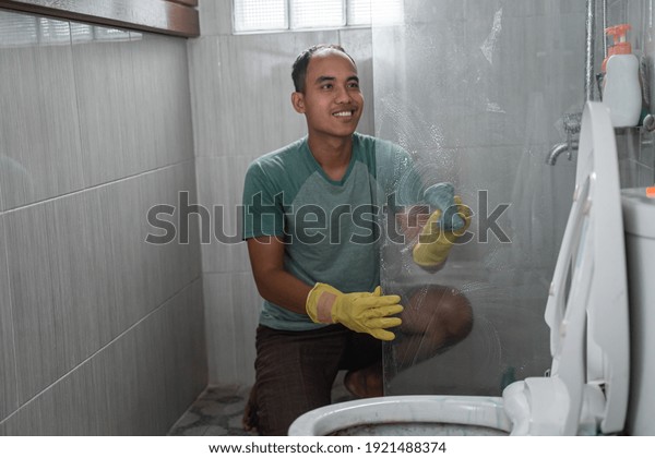 a man wearing gloves cleaned the toilet glass\
divider in the bathroom