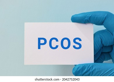 Man Wearing Gloves Holding A Card With The Text PCOS (Polycystic Ovary Syndrome). Women Health Awareness Concept. 