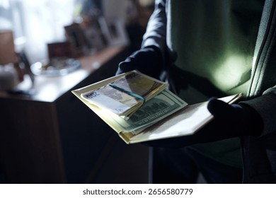 Man wearing gloves holding stack of euro and dollar banknotes in hands indoors, counting money with partial body visible, background out of focus