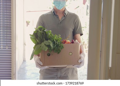 Man Wearing Gloves And Mask Home Delivering Or Collecting Food Box, Food Bank, Volunteer Holding Grocery Box For Donation Concept