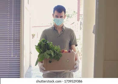 Man Wearing Gloves And Mask Home Delivering Or Collecting Food Box, Food Bank, Volunteer Holding Grocery Box For Donation Concept