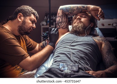 Man Wearing Gloves Works In Tatoo Salon./Tattoo Specialist Makes Tattoo Pictures In Salon.