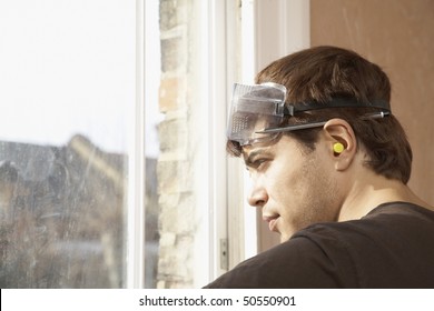 Man Wearing Goggles And Earplugs, Looking Out Window