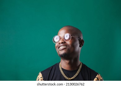 Man Wearing Gold Teeth Jewellery, Also Known As Teeth Grillsteeth Slugs, Photographed Against A Dark Green Background.