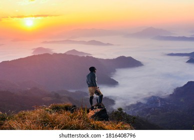 Man Wearing Gray Long Sleeved Shirt And Brown Shorts Holding Black Dslr Camera On Mountain. Focus On Man.