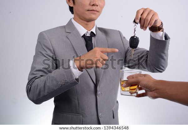 The man wearing a gray suit,\
tied with a black necktie, put his finger on the black car key to\
see to refuse to drink. That his friend gave him a glass of\
liquor