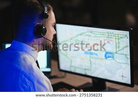 Man wearing a headset dispatching freight and managing transportation while tracking vehicles on a computer map