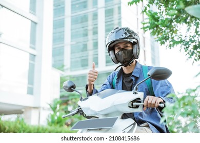 Man wearing helmet with thumbs up on a motorcycle